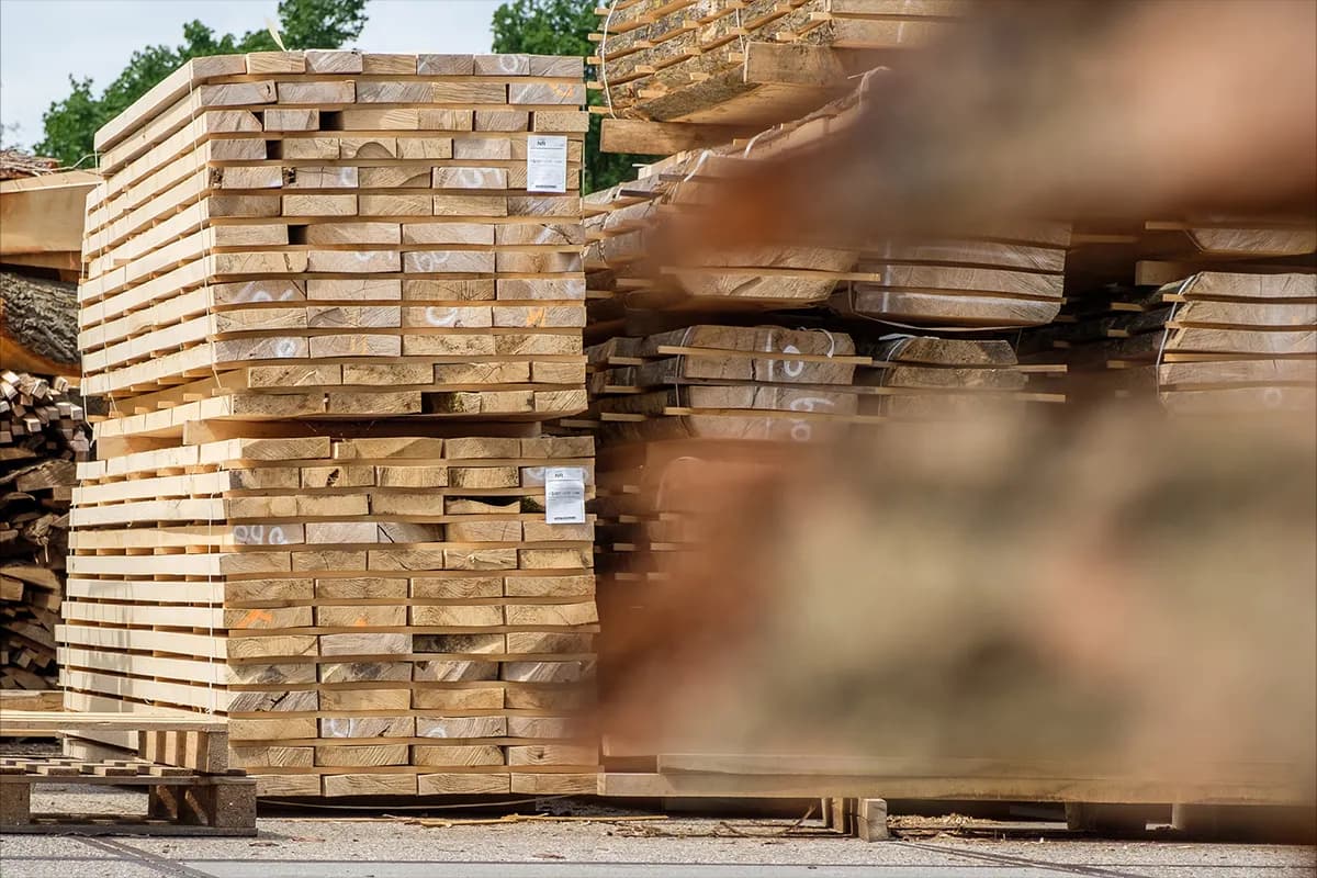 Stapels gezaagd essenhout op pallets, buiten op de houtopslag.