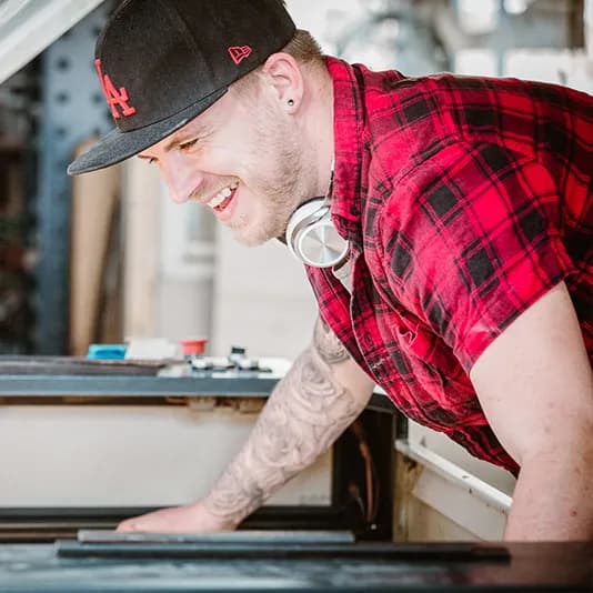 Een lachende medewerker legt een plank in de lasersnijder.