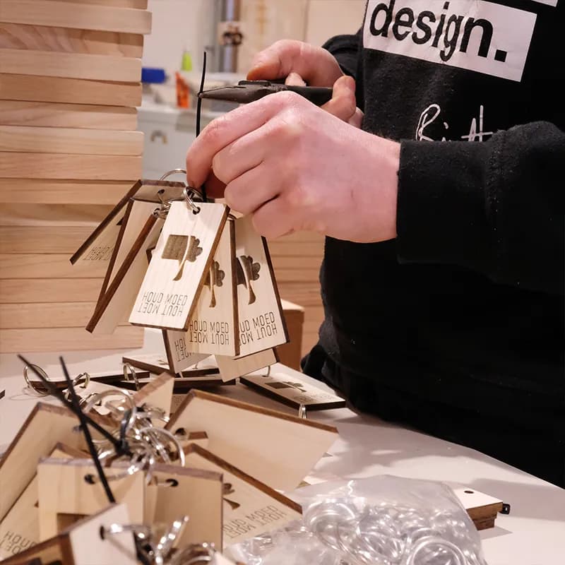 Houten sleutelhangers met sleutelring afgewerkt.