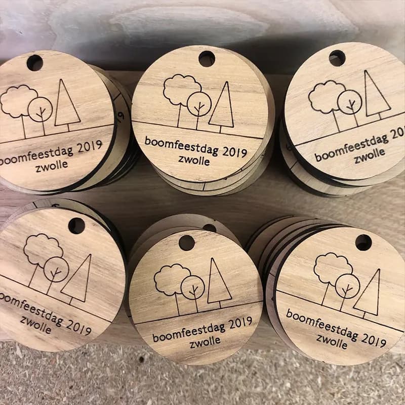 Stapeltjes ronde houten sleutelhangers met een gegraveerd ontwerp.