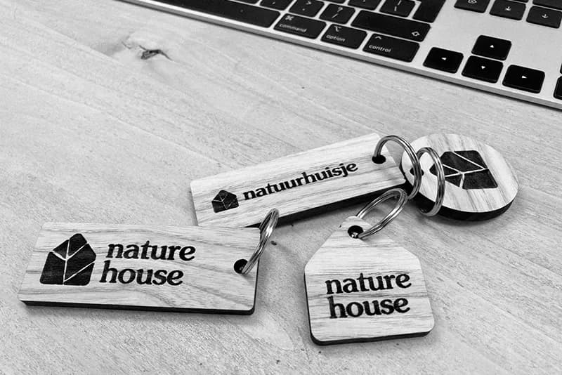 Houten sleutelhangers in vier vormen met gegraveerd logo van natuurhuisje naturehouse