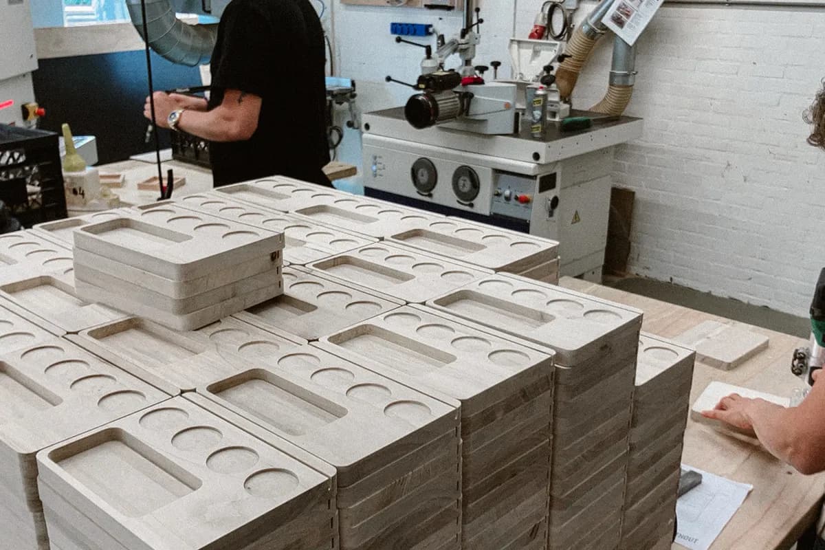 Gestapelde houten planken met ronde uitsparingen op een werktafel in de werkplaats van Binthout.